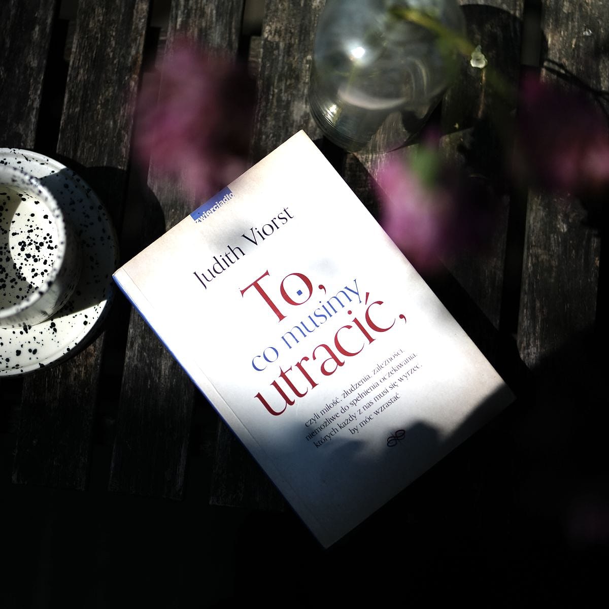 Książka „To, co musimy utracić” Judith Viorst na drewnianym stole obok filiżanki